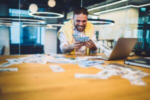 Excited male millionaire happy with triumph win in online web lottery on modern laptop computer, suc