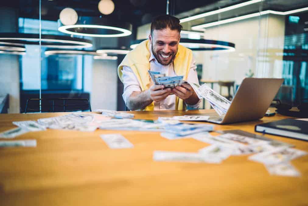 Excited male millionaire happy with triumph win in online web lottery on modern laptop computer, suc