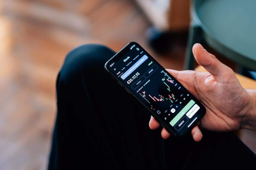 persons hand holding a phone showing a bitcoin chart - Image of Cryptocurrency, "cryptocurrency inve